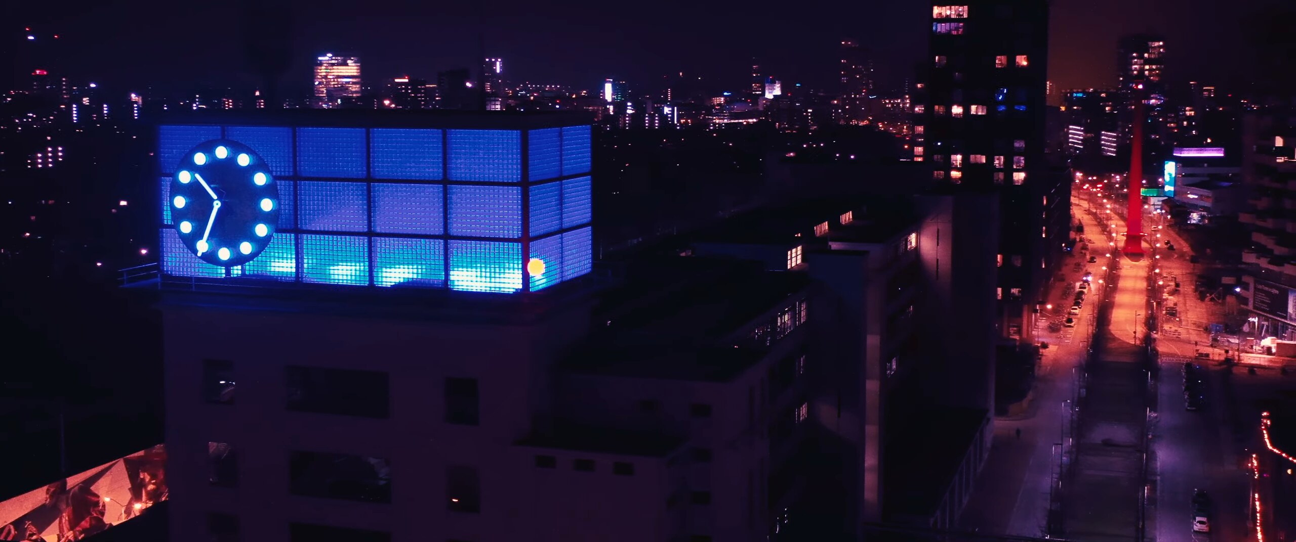 De stad bij nacht vanaf een dak, met een verlichte klok