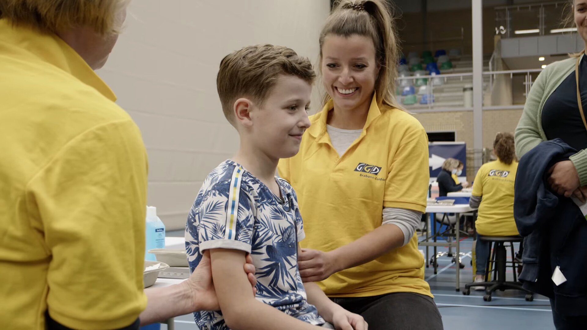 Lachende GGD-medewerker met een jongen bij de vaccinatie